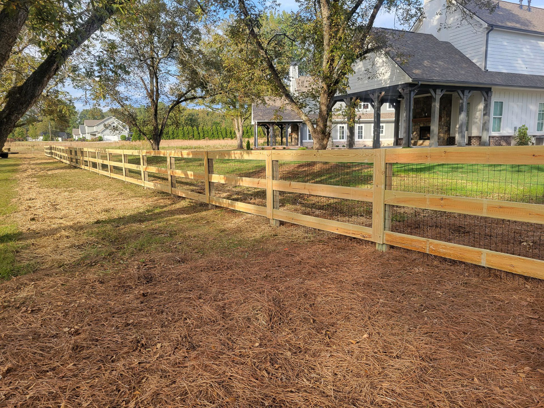 Three-rail wood farm fence with wire mesh